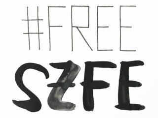 Der handgeschriebene Text auf weißem Hintergrund lautet in großen, fetten Buchstaben „#FREE SZFE“.