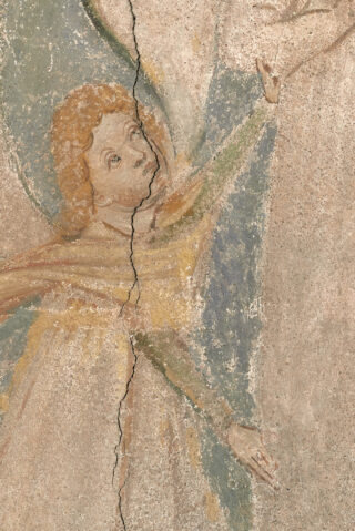 Verblasstes Freskogemälde einer Figur mit lockigem Haar und ausgestrecktem Arm, geteilt durch einen vertikalen Riss durch das Bild.