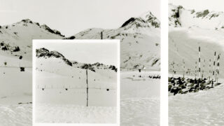 Schneebedeckte Berge mit mehreren vertikalen Stangen oder Markierungen im Vordergrund und Mittelgrund; ein zentraler Einschub hebt eine Stange vor der verschneiten Landschaft hervor.