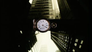 Eine Taschenuhr ist über eine Schwarzweißansicht hoher Gebäude gelegt, die von der Straßenebene aus gesehen nach oben zeigt.