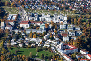 Luftaufnahme eines Stadtgebiets mit modernen Wohnhäusern, Grünflächen, von Bäumen gesäumten Straßen und Wohnhäusern im Herbst.