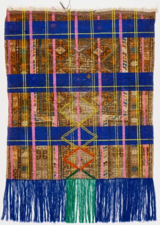 Ein gewebter Stoff mit geometrischen Mustern und horizontalen blauen, rosa und gelben Streifen mit blauen und grünen Fransen am unteren Rand.