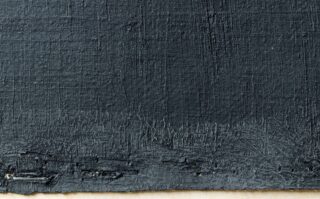 Nahaufnahme einer strukturierten schwarz lackierten Oberfläche mit sichtbaren Pinselstrichen und unebenen Kanten an der Unterseite.