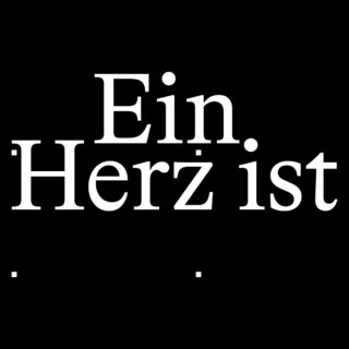 Weißer deutscher Text „Ein Herz ist.“ auf schwarzem Hintergrund, wobei jedes Wort in einer neuen Zeile steht und sich unter den Wörtern zwei Punkte befinden.