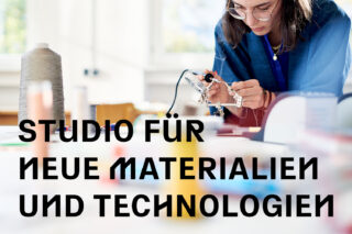 Eine Person arbeitet mit Werkzeugen an einem mit Materialien bedeckten Schreibtisch, über dem in fetten Buchstaben der Text „Studio für neue Materialien und Technologien“ steht.