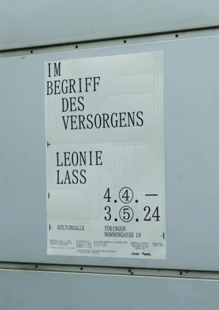 An einer grauen Wand ist ein Plakat angebracht, das für „Im Begriff des Versorgens“ von Leonie Lass in der Kulturhalle Tübingen vom 4. April bis 5. Mai 2024 wirbt.