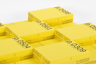 Stapel gelber rechteckiger Kästen mit schwarzem Text und Zahlen sind in einem ordentlichen, gitterartigen Muster auf einer weißen Oberfläche angeordnet.