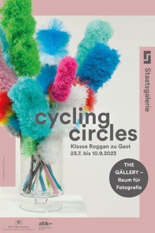 In einer Glasvase befinden sich bunte Staubwedel mit Ausstellungsinformationen zur Ausstellung „Radfahren im Kreis“ in der Staatsgalerie, die vom 23. Juli bis 10. September 2023 stattfindet.