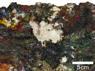 Dicke, strukturierte Schichten gemischter Ölfarbe in verschiedenen Farben, mit Fokus auf einem zentralen weißen Bereich; der Maßstab zeigt 5 Zentimeter an.