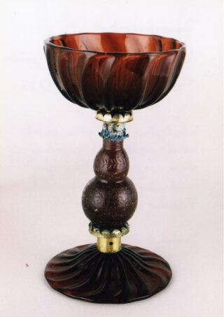 Ein brauner, verzierter Glaskelch mit abgerundeter Schale, dekorativem Stiel und ausgestelltem Boden, mit goldfarbenen Akzenten und strukturierten Mustern.