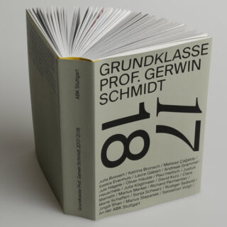 Ein Buch mit dem Titel „GRUNDKLASSE PROF. GERWIN SCHMIDT 17 18“ steht aufrecht, auf dem Cover ist ein sichtbarer Text mit Namensauflistung zu sehen.