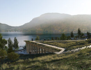 Ein See in den Bergen, im Vordergrund eine Treppe und ein mit gras bewachsener Aussichtspunkt, der auf Säulen ruht, darunter ein offener Raum.