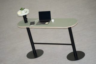 Ein Stehpult mit einem Laptop, einem Tablet, einem Paar kabelloser Ohrhörer, einer Lampe und einer kleinen Topfpflanze auf einem hellen Boden.