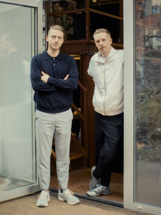 Zwei Männer stehen in einer geöffneten Glastür.