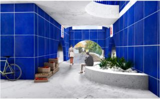 Ein moderner Gehweg mit blau gefliesten Wänden, einem geschwungenen Blumenkasten mit Grünpflanzen, Kisten mit roten Erzeugnissen, einem Fahrrad und zwei Personen, die sich in der Nähe einer gewölbten Öffnung unterhalten, von der aus Bäume zu sehen sind.