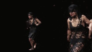 Eine Person in einem schwarzen Kleid scheint sich vor einem dunklen Hintergrund in Partikel aufzulösen. Die Figur ist in zwei verschiedenen Posen dargestellt.