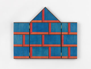 Geometrisches Wandbild in Form eines Hauses, bestehend aus aufklappbaren blauen und roten Paneelen mit einem sich wiederholenden rechteckigen Muster.