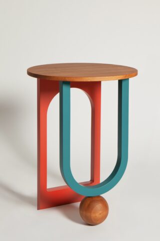 Ein moderner Beistelltisch mit einer runden Holzplatte, einem geometrischen Sockel in Rot und Teal und einer Holzkugel, die eine Seite stützt.