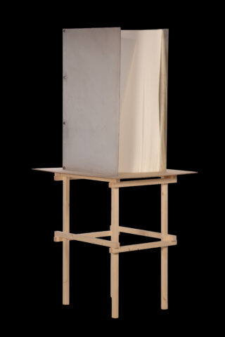 Ein metallischer Sichtschutz steht auf einem Tisch mit hellem Holzrahmen vor einem schwarzen Hintergrund.