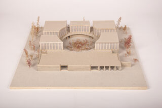 Architekturmodell, das sechs rechteckige Gebäude zeigt, die kreisförmig um einen zentralen Hof mit Bäumen angeordnet sind, sowie ein langgestrecktes Gebäude davor, alle auf einer quadratischen Grundfläche.