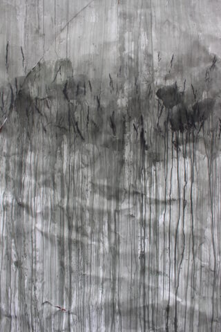 Graue und schwarze abstrakte Flecken und Schlieren verlaufen vertikal über eine strukturierte Oberfläche, die an Wasser- oder Tintentropfen auf einer Wand erinnert.