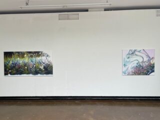 Zwei abstrakte Gemälde hängen in einer Galerie an einer schlichten weißen Wand. Das linke Bild ist farbenfroh und dicht, während das rechte hellere, pastellfarbene Töne und fließende Linien aufweist.