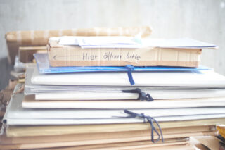 Ein Stapel großer Mappen und Pakete, wobei das oberste Paket handschriftlich mit 