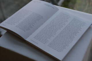 Ein aufgeschlagenes Buch mit Text in englischer und koreanischer Sprache, das auf einer weißen Fläche in der Nähe eines Fensters mit Tageslicht liegt.