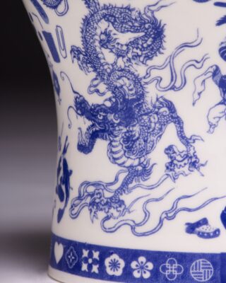 Nahaufnahme einer weißen Porzellanvase, verziert mit komplizierten blauen Drachen- und Blumenmustern.