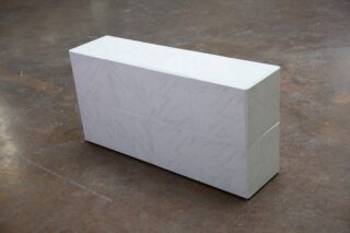 Ein rechteckiger weißer Block mit einem marmorähnlichen Muster liegt auf einem Betonboden.