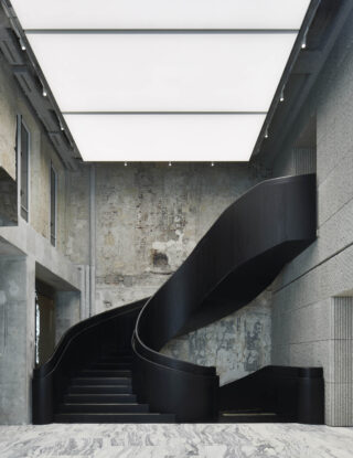 Eine moderne schwarze Wendeltreppe mit massivem Geländer steht in einem minimalistischen Innenraum mit Sichtbetonwänden und einer großen beleuchteten Deckenplatte.