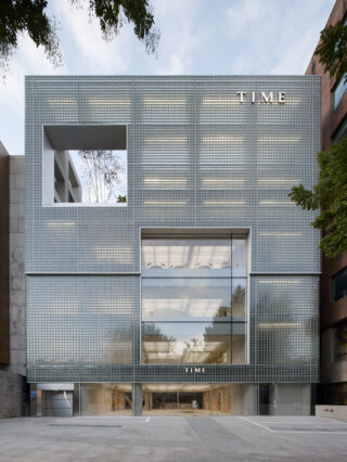 Modernes Gebäude mit einer perforierten Metallfassade, großen Glasfenstern und dem Wort 