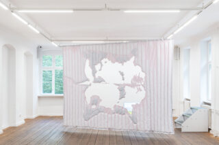 Ein pastellrosa und weißer Vorhang mit einem großen, unregelmäßig geformten Ausschnitt hängt in einem hellen Galerieraum mit Holzboden und weißen Wänden.