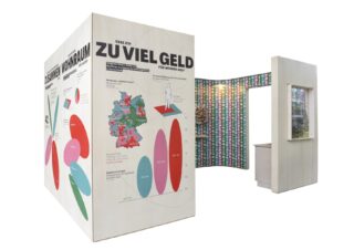 Ein moderner Messestand mit großen Infografik-Tafeln, auf denen Diagramme, Grafiken und eine Karte von Deutschland zu sehen sind; die Innenwände sind mit bunten, gemusterten Quadraten verziert.