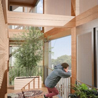 Eine Person lehnt an einem Balkongeländer in einem modernen Holzgebäude mit großen Fenstern, einem Topfbaum und Pflanzen.