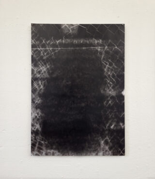 Ein abstraktes Kunstwerk in Schwarz-Weiß, das eine dunkle zentrale Form mit helleren, gitterartigen Mustern an den Rändern zeigt und an einer weißen Wand angebracht ist.
