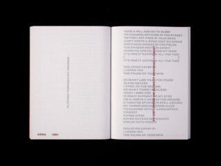Ein aufgeschlagenes Buch zeigt zwei weiße Seiten mit schwarzem und rotem Text, darunter ein Gedicht und Angaben zur Veröffentlichung: „ARS A 1981“. Die Zeilen des Gedichts sind linksbündig ausgerichtet, und einige sind rot durchgestrichen.