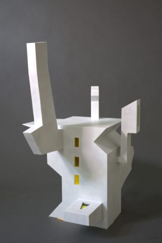 Weiße, abstrakte, geometrische Skulptur mit kantigen Formen, hervorstehenden Säulen, drei gelben, rechteckigen Fenstern und einem grauen Hintergrund.