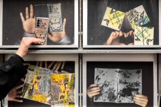 Hände, die vier verschiedene Kunstdrucke oder Zines halten, präsentiert in einem Raster aus Bilderrahmen.