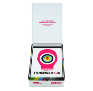 Eine geöffnete „Filmspiration“-Kartenschachtel, auf deren Innendeckel ein Zitat zu sehen ist und aus der eine Karte mit einem stilisierten Kopf und dem Text „Hasta la Vista, Baby!“ herausragt.